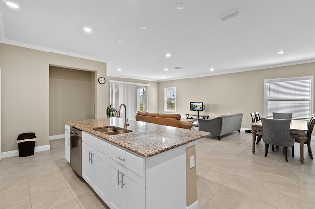 kitchen featuring light stone counters, dishwasher, a kitchen island with sink, sink, and white cabinets