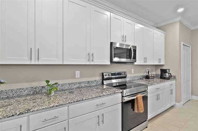 kitchen with white cabinets, appliances with stainless steel finishes, light tile patterned floors, crown molding, and light stone countertops