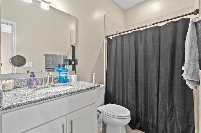 bathroom with curtained shower, vanity, and toilet