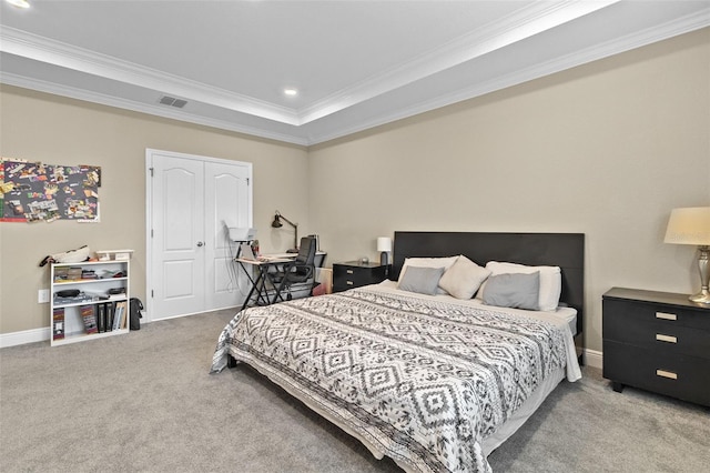 carpeted bedroom featuring crown molding, a tray ceiling, and a closet