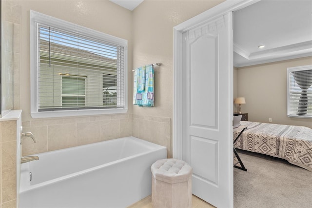 bathroom featuring a tub to relax in, a raised ceiling, and ornamental molding