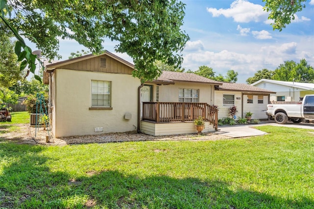 single story home with central air condition unit, a deck, and a front yard