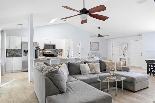 living room featuring light wood-type flooring, ceiling fan, and high vaulted ceiling