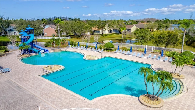 view of swimming pool featuring a water view, a water slide, and a patio area