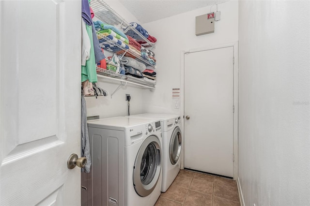 laundry area with a textured ceiling, separate washer and dryer, and light tile patterned floors