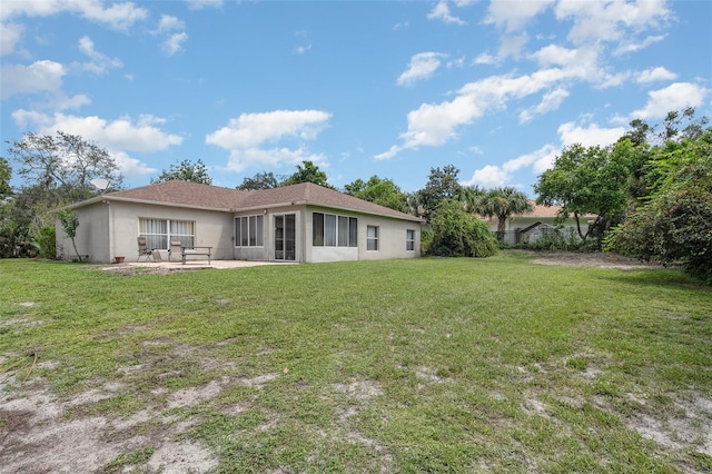 rear view of house with a sunroom, a patio, and a yard