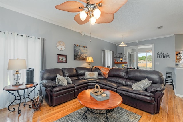 living room featuring ornamental molding, light wood-type flooring, ceiling fan, and a textured ceiling