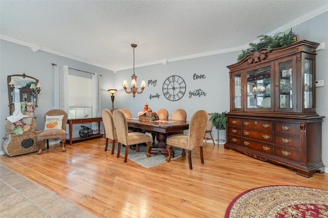 dining space featuring ornamental molding, a textured ceiling, light hardwood / wood-style flooring, and a chandelier