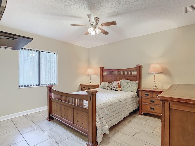 bedroom with a textured ceiling, light tile patterned floors, and ceiling fan