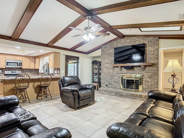 tiled living room featuring vaulted ceiling with beams, a brick fireplace, sink, and ceiling fan