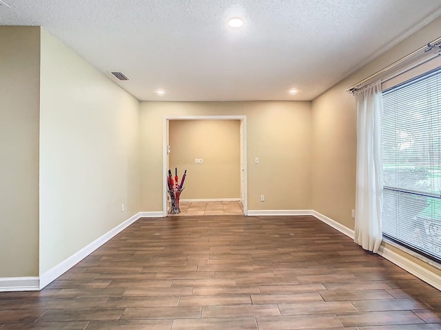 empty room with a textured ceiling and dark hardwood / wood-style flooring