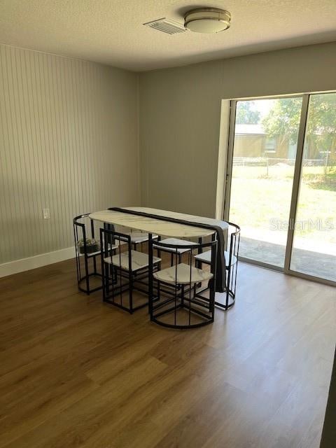 dining room with a textured ceiling and dark hardwood / wood-style floors