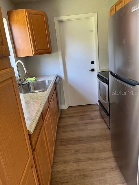 kitchen with light wood-type flooring, sink, and stainless steel appliances