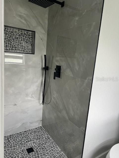 bathroom with a tile shower and toilet