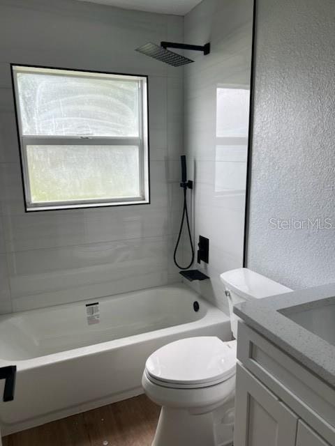 full bathroom featuring wood-type flooring, tiled shower / bath, vanity, and toilet