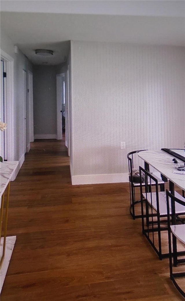 dining space with wood walls and dark wood-type flooring