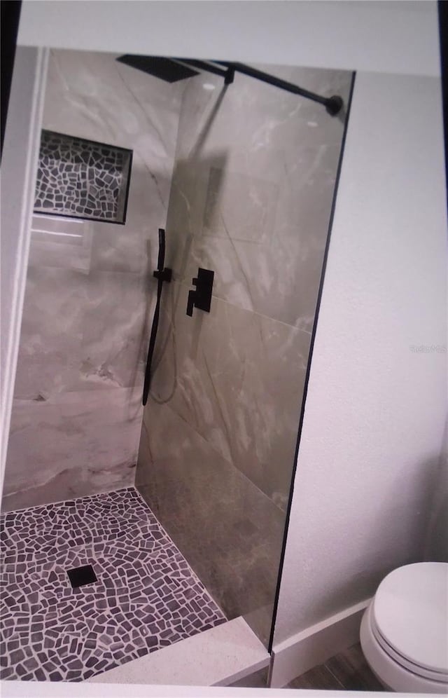 bathroom featuring a tile shower and toilet