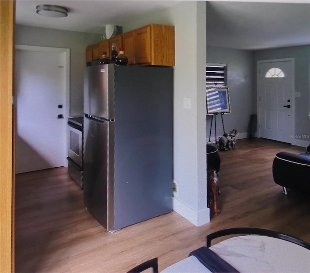 kitchen with light hardwood / wood-style flooring, black range oven, and stainless steel fridge