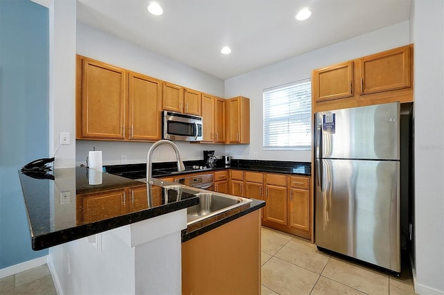 kitchen with dark stone countertops, light tile patterned flooring, kitchen peninsula, a breakfast bar area, and stainless steel appliances