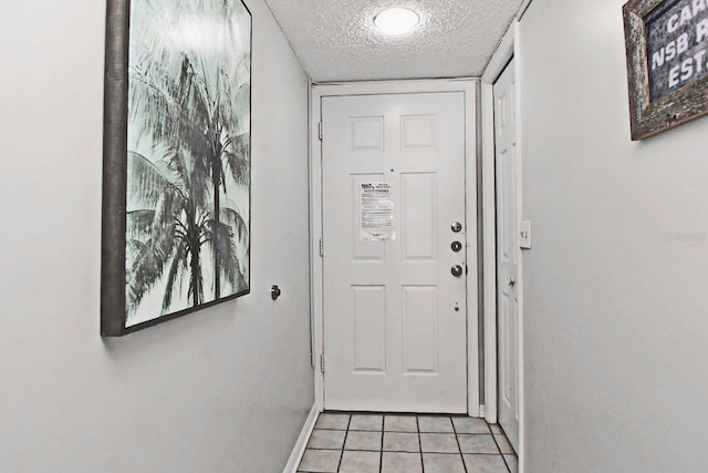 entryway with a textured ceiling, baseboards, and light tile patterned floors