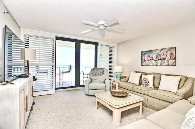 living area with a textured ceiling, a ceiling fan, and light colored carpet