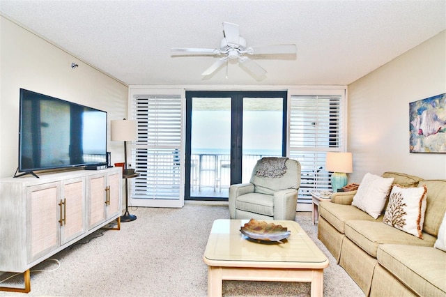 carpeted living room featuring ceiling fan and a textured ceiling