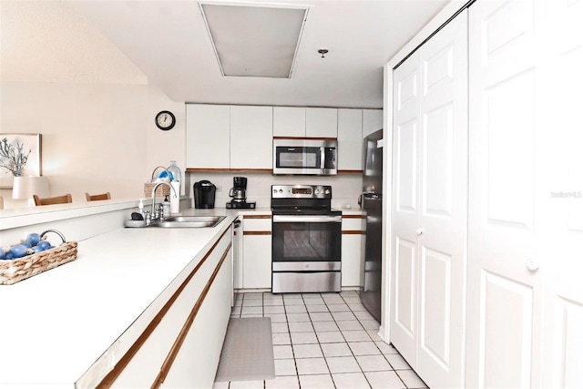 kitchen featuring light tile patterned floors, appliances with stainless steel finishes, light countertops, white cabinetry, and a sink