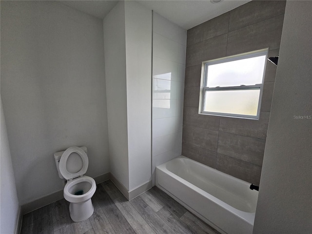 bathroom featuring tiled shower / bath, wood-type flooring, and toilet