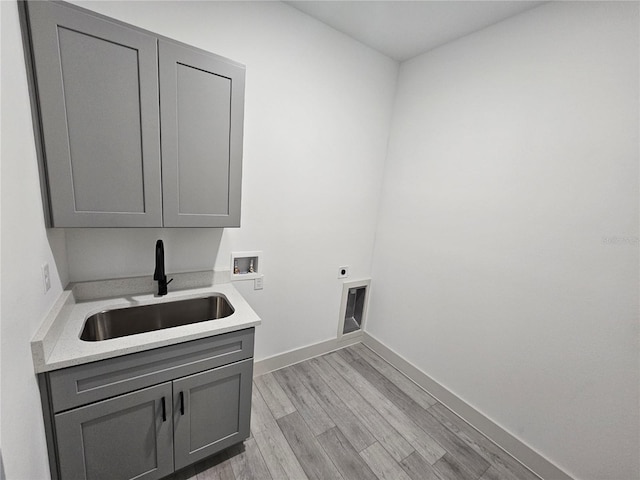 laundry room featuring hookup for a washing machine, hookup for an electric dryer, sink, light hardwood / wood-style floors, and cabinets