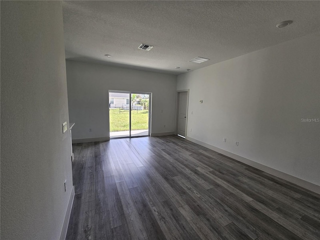 empty room with a textured ceiling and dark hardwood / wood-style floors