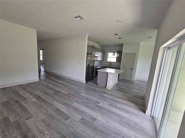 kitchen with a kitchen island, hardwood / wood-style floors, stainless steel fridge, sink, and decorative light fixtures