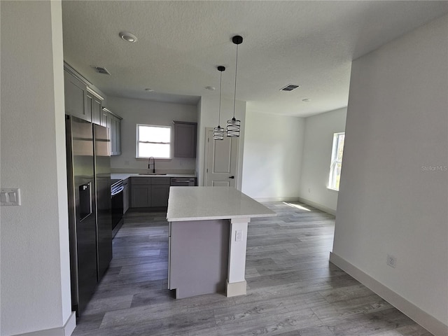 kitchen with hanging light fixtures, dark hardwood / wood-style flooring, high quality fridge, gray cabinets, and a center island