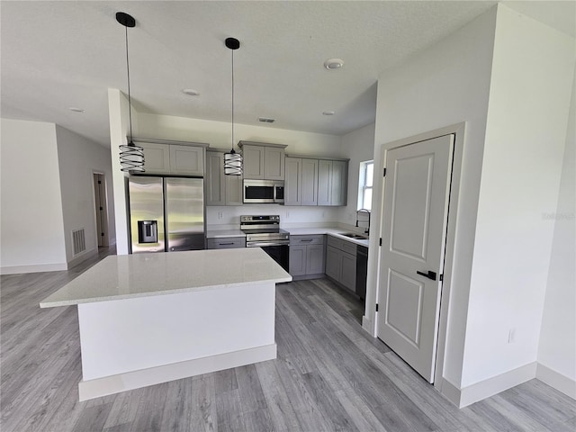 kitchen featuring gray cabinetry, sink, a kitchen island, stainless steel appliances, and light hardwood / wood-style flooring