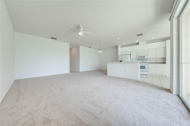 unfurnished living room with a textured ceiling, a healthy amount of sunlight, ceiling fan, and light colored carpet