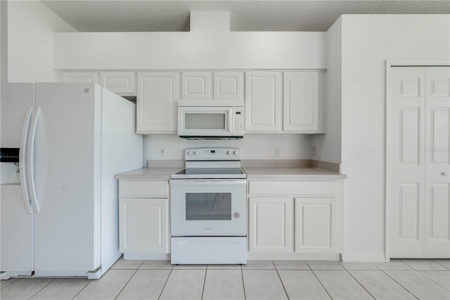 kitchen with a textured ceiling, white appliances, and white cabinets