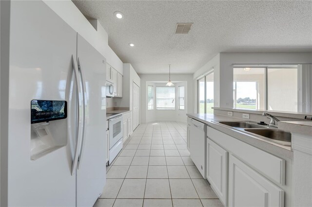 kitchen with white cabinets, sink, white appliances, and a wealth of natural light