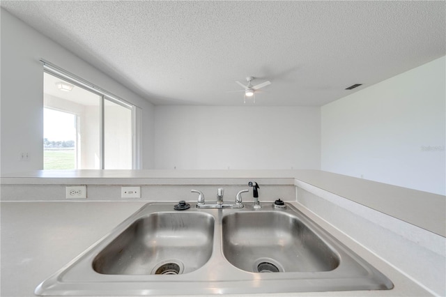 kitchen with a textured ceiling, sink, and ceiling fan