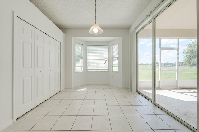 interior space with access to outside, a textured ceiling, a closet, and light tile patterned floors