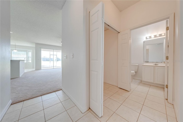 hall featuring light colored carpet and a textured ceiling