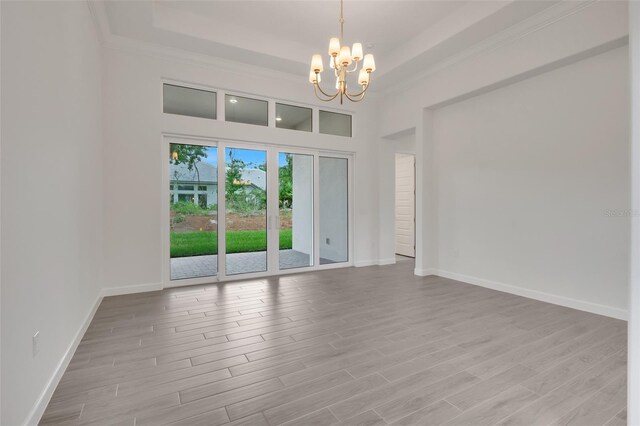 empty room featuring ornamental molding, light hardwood / wood-style flooring, and a notable chandelier