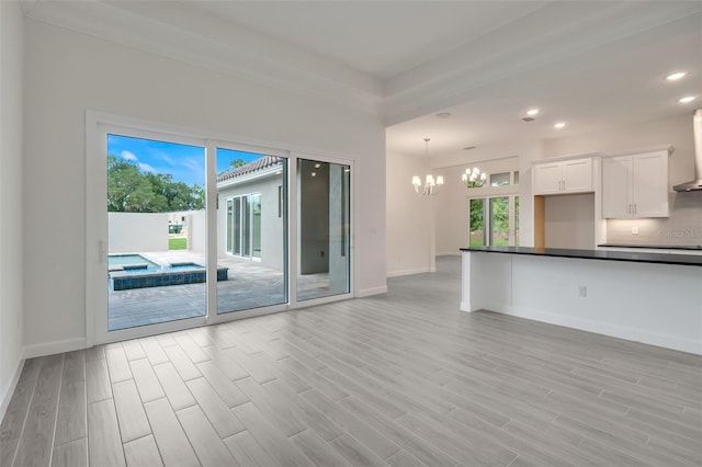 unfurnished living room with light hardwood / wood-style flooring and a notable chandelier