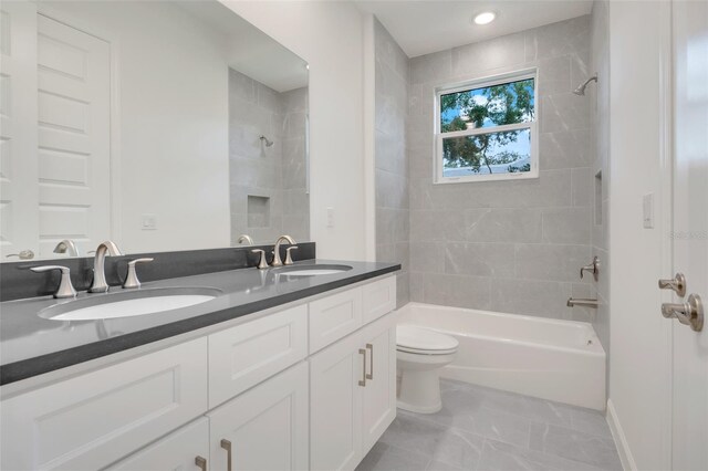 full bathroom featuring tiled shower / bath combo, vanity, and toilet