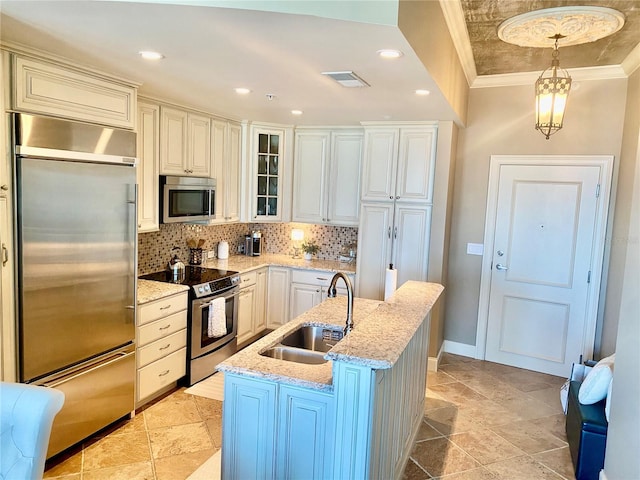 kitchen featuring appliances with stainless steel finishes, pendant lighting, a center island with sink, ornamental molding, and sink