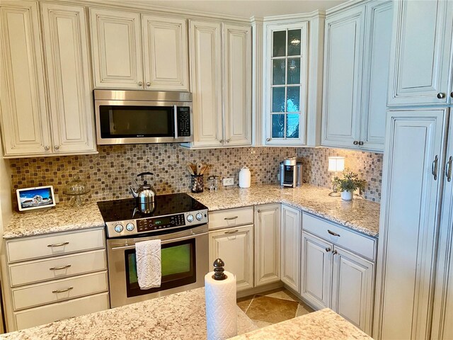 kitchen featuring appliances with stainless steel finishes, decorative backsplash, and light stone counters