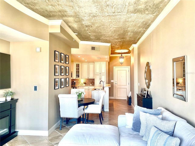 tiled living room featuring sink and crown molding