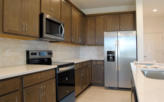 14569 Crestavista Dr, Clermont, FL 34714 - kitchen with appliances with stainless steel finishes, light stone counters, decorative backsplash, recessed lighting, and light tile patterned floors
