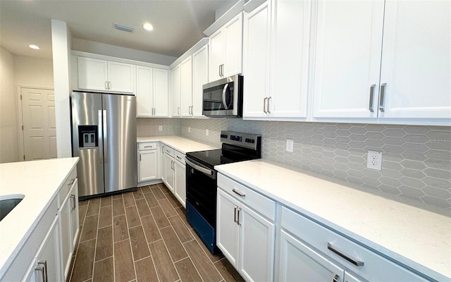 kitchen with visible vents, wood tiled floor, decorative backsplash, white cabinets, and stainless steel appliances