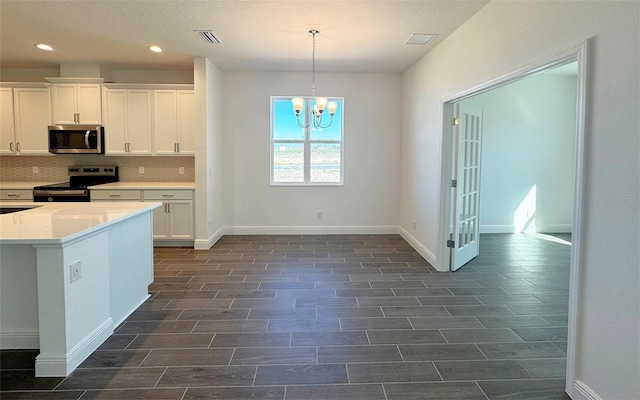 kitchen with visible vents, wood finish floors, appliances with stainless steel finishes, white cabinetry, and a chandelier