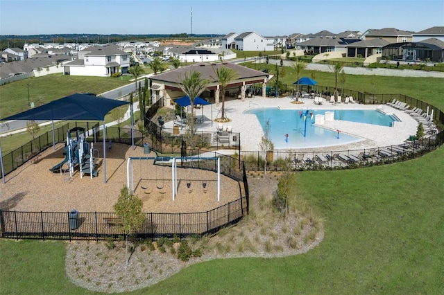 pool with playground community, a residential view, a yard, and fence