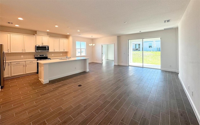 kitchen featuring visible vents, dark wood-type flooring, open floor plan, stainless steel appliances, and a sink